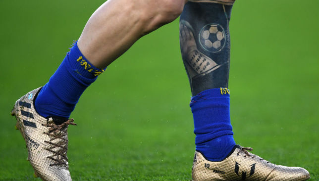 A few visible tattoos on Messi's left leg.