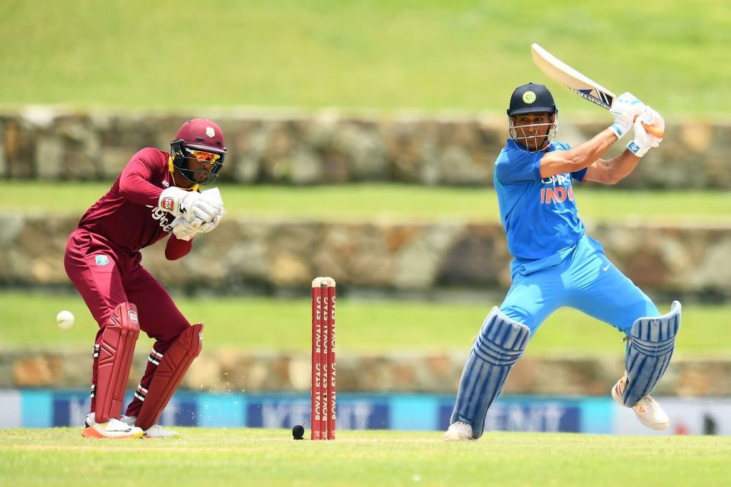India's MS Dhoni (R) plays a shot as West Indies' wicketkeeper Shai Hope looks on during the third One Day International (ODI) match between West Indies and India, at the Sir Vivian Richards Cricket Ground in St. John's, Antigua, on June 30, 2107. / AFP PHOTO / Jewel SAMAD (Photo credit should read JEWEL SAMAD/AFP/Getty Images)