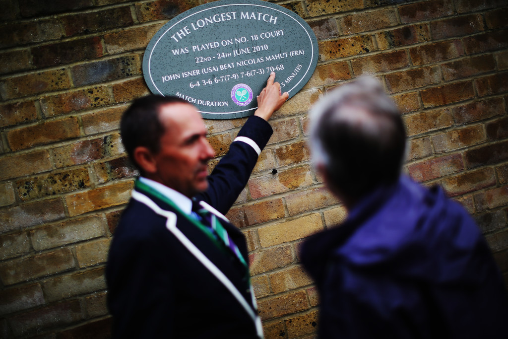 LONDON, ENGLAND - JUNE 28: A Wimbledon official points out the plague that is on the outside of Court 18 to commemorate the longest match which was between John Isner and Nicolas Mahut in 2010 on day six of the Wimbledon Lawn Tennis Championships at the All England Lawn Tennis and Croquet Club at Wimbledon on June 28, 2014 in London, England. (Photo by Dan Kitwood/Getty Images)