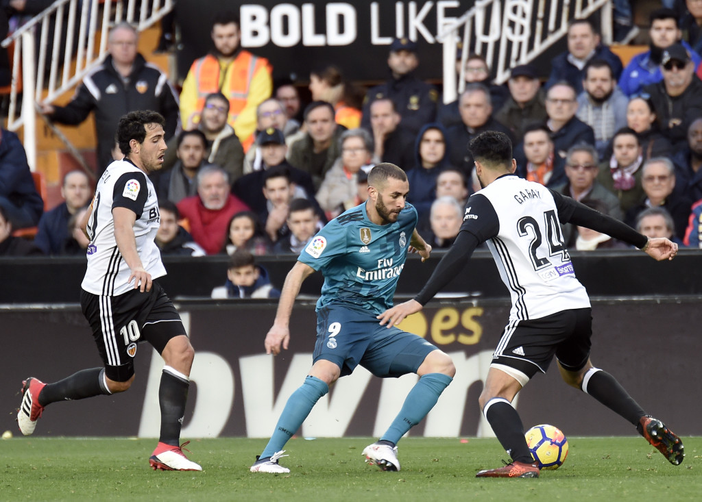 Real Madrid's French forward Karim Benzema (C) vies with Valencia's Argentinian defender Ezequiel Garay (R) as Valencia's Spanish midfielder Daniel Parejo approaches during the Spanish league football match between Valencia CF and Real Madrid CF at the Mestalla stadium in Valencia on January 27, 2018. / AFP PHOTO / JOSE JORDAN (Photo credit should read JOSE JORDAN/AFP/Getty Images)