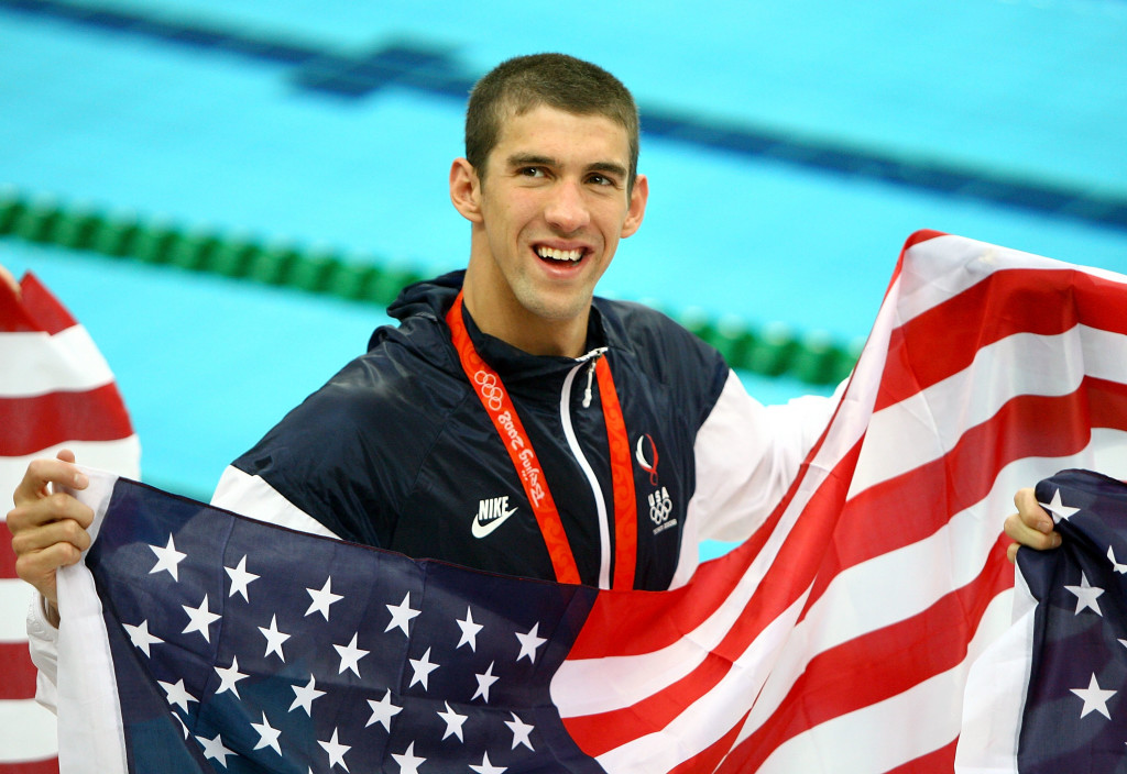 BEIJING - AUGUST 17: Michael Phelps of the United States smiles with the American flag as he wears his eighth gold medal after the Men's 4x100 Medley Relay at the National Aquatics Centre during Day 9 of the Beijing 2008 Olympic Games on August 17, 2008 in Beijing, China. (Photo by Adam Pretty/Getty Images)