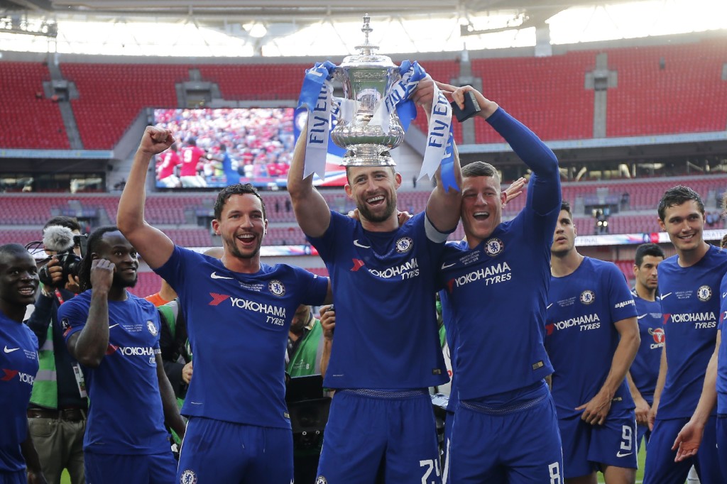 Chelsea's English defender, captain Gary Cahill (C), Chelsea's English midfielder Danny Drinkwater (centre L) and Chelsea's English midfielder Ross Barkley (centre R) hold up the trophy as Chelsea's players celebrate their win on the pitch after the English FA Cup final football match between Chelsea and Manchester United at Wembley stadium in London on May 19, 2018. - Chelsea beat Manchester United 1-0 to lift the FA Cup thanks to Eden Hazard's penalty at Wembley on Saturday to salvage a disappointing season. (Photo by Ian KINGTON / AFP) / NOT FOR MARKETING OR ADVERTISING USE / RESTRICTED TO EDITORIAL USE (Photo credit should read IAN KINGTON/AFP/Getty Images)