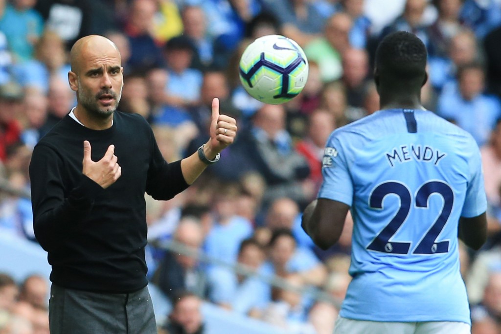 Manchester City's Spanish manager Pep Guardiola (L) throws the ball to Manchester City's French defender Benjamin Mendy (R) during the English Premier League football match between Manchester City and Huddersfield Town at the Etihad Stadium in Manchester, north west England, on August 19, 2018. (Photo by Lindsey PARNABY / AFP) / RESTRICTED TO EDITORIAL USE. No use with unauthorized audio, video, data, fixture lists, club/league logos or 'live' services. Online in-match use limited to 120 images. An additional 40 images may be used in extra time. No video emulation. Social media in-match use limited to 120 images. An additional 40 images may be used in extra time. No use in betting publications, games or single club/league/player publications. / (Photo credit should read LINDSEY PARNABY/AFP/Getty Images)